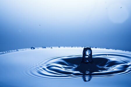 drop of water falling down in the waterの写真素材