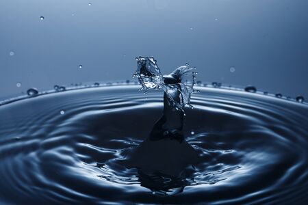 drop of water falling down in the waterの写真素材