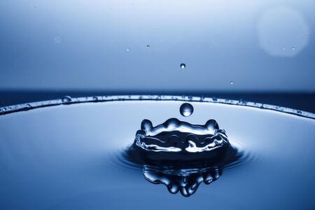 drop of water falling down in the waterの写真素材