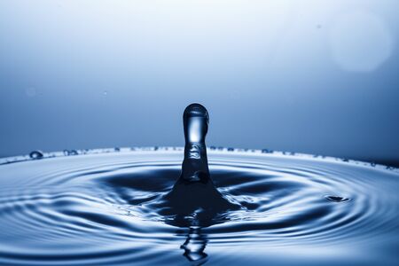 drop of water falling down in the waterの写真素材