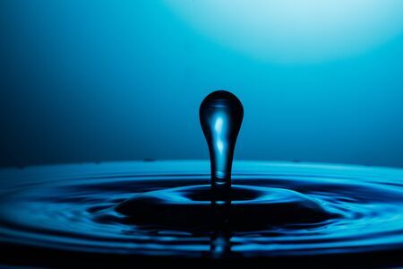 drop of water falling down in the waterの写真素材