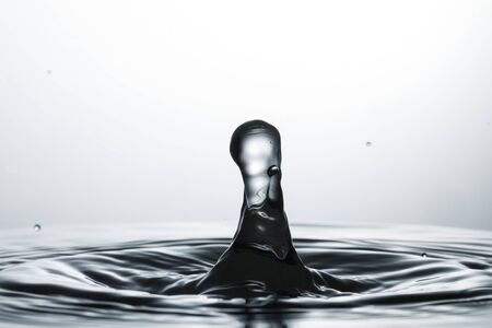 drop of water falling down in the waterの写真素材
