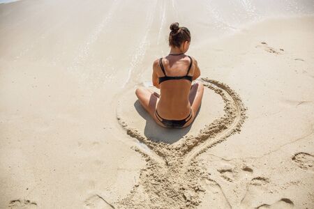 beautiful girl in the Lotus position on the beachの写真素材