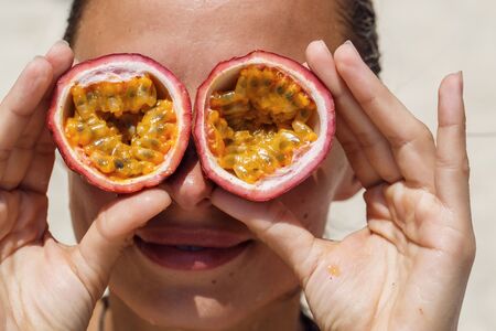 beautiful girl on the beach with passion fruit for eyesの写真素材