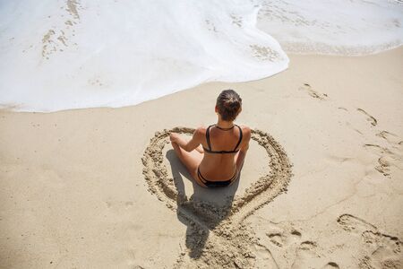 beautiful girl in the Lotus position on the beachの写真素材