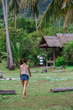 a girl in a white t-shirt and blue shorts walks through the jungleの写真素材