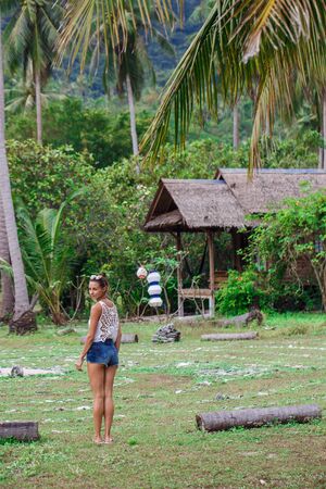 a girl in a white t-shirt and blue shorts walks through the jungleの写真素材
