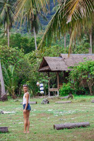 a girl in a white t-shirt and blue shorts walks through the jungleの写真素材