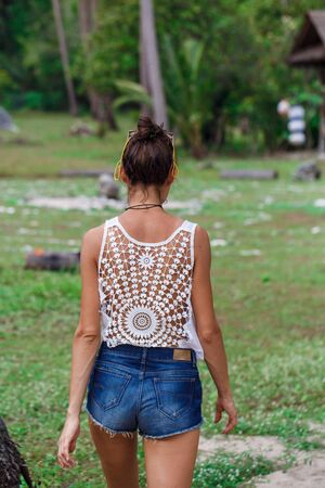 a girl in a white t-shirt and blue shorts walks through the jungleの写真素材