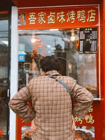 Shangai, China - December 28, 2019: Chinese local old woman/lady is choosing what food to buy from...