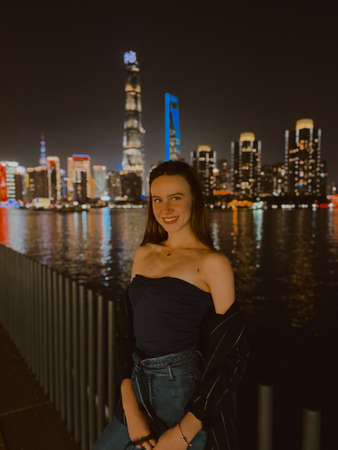 Night in the city of skyscrapers. Young girl by the river. Evening view. Romantic atmosphere in the Bund, Shanghai, China.の写真素材