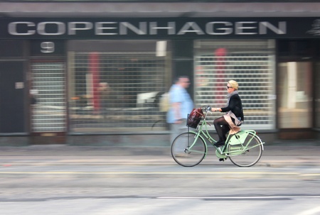COPENHAGEN - MAY 20, 2012: Female cyclist riding quickly along Ved Vesterport street in Copenhagen on May 20, 2012. Intentional in camera motion blur.のeditorial素材