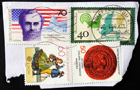 GERMANY - CIRCA 1981: A set of four stamps printed by Germany shows Marburg University emblem, portraits of German poet Eduard Morike and American statesman Carl Schurz, circa 1981 のeditorial素材