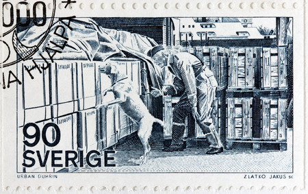 SWEDEN - CIRCA 1975: A stamp printed by SWEDEN shows Swedish Customs Officer with specially trained dog used to search for narcotics, circa 1975のeditorial素材