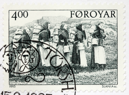LUGA, RUSSIA - JUNE 25, 2016: A stamp printed by FAROE ISLANDS shows dairymaids carrying buckets, circa 1995.のeditorial素材