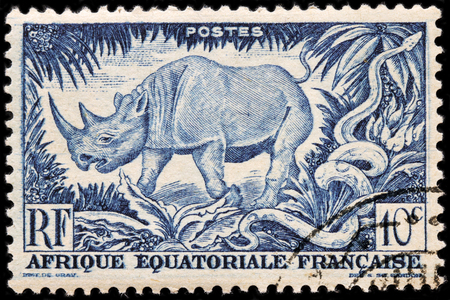 LUGA, RUSSIA - APRIL 12, 2016: A stamp printed by FRENCH EQUATORIAL AFRICA shows Black Rhinoceros and African Rock Python, circa 1947.のeditorial素材