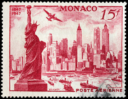 LUGA, RUSSIA - NOVEMBER 29, 2016: A stamp printed by MONACO shows beautiful view of Manhattan with Statue of Liberty and airplane Douglas DB 7 Boston over New York City, circa 1947のeditorial素材