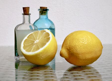 Still life with two ripe juicy lemons and cold fresh lemonade in two small vintage glass botlles against a high key background with space for your text. Selective and soft focus.     の写真素材