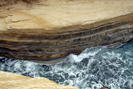 Waves hit the a clif gap where somebody forget bottle and plastic cupの写真素材