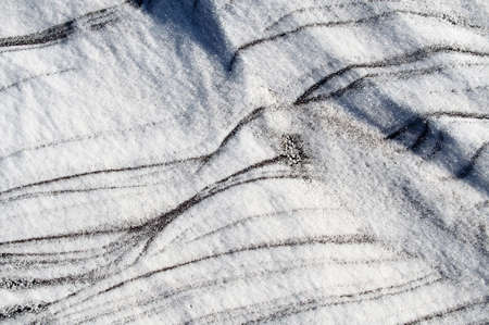 Sleet at a wind sticks to the ground, forming beautiful reliefsの写真素材