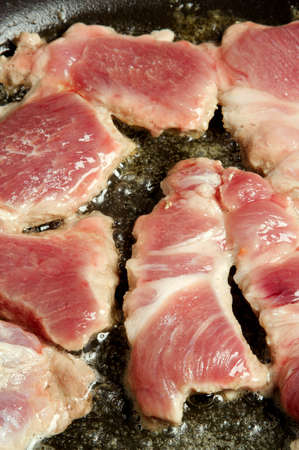 Preparation of slices of pork on a frying pan with the help of gasの写真素材
