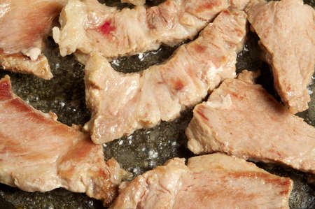 Preparation of slices of pork on a frying pan with the help of gasの写真素材
