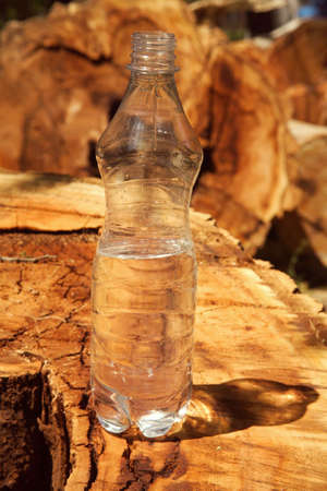 Bottle of water on a background of an old rotten tree.の写真素材