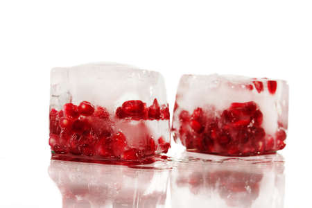 Berries of a ripe pomegranate in ice on a white background.の写真素材