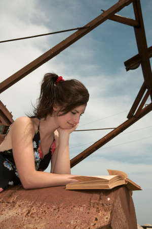Girl reads book on the old rusty mechanismの写真素材