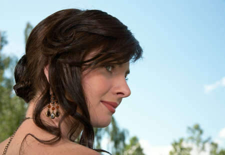 Portrait of a brunette with a classical hairdress on a background of the dark blue sky.