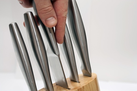 The hand takes out a kitchen knife from a set of knifes for the cook