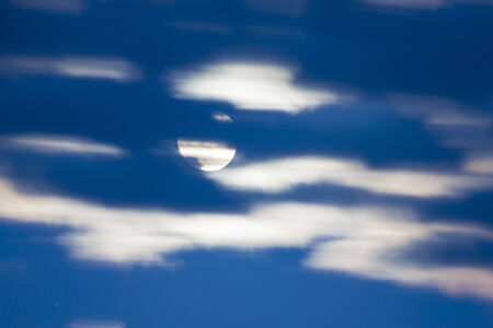 Bright light of the moon in the night cloudy skyの写真素材