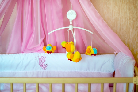 Musical roundabout with soft toys, mobile  in a crib in the roomの写真素材