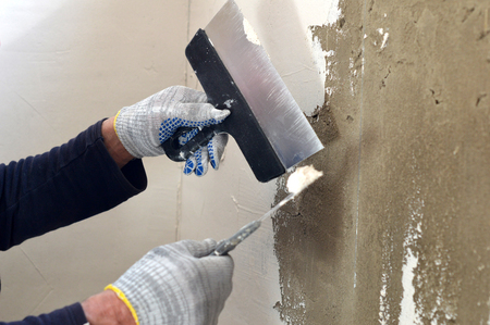 Process putty gray concrete wall with two metal spatulasの写真素材