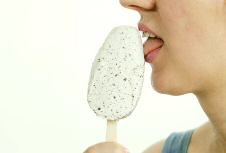Woman eating white ice cream on a light background