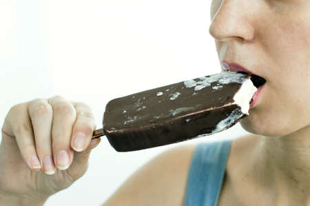 Woman eats ice cream with chocolate on a light background