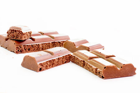 Pieces of tile porous milk chocolate on white background
