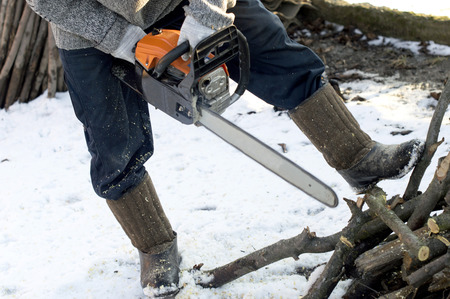 The process of cutting wood using a chainsaw in the open air
