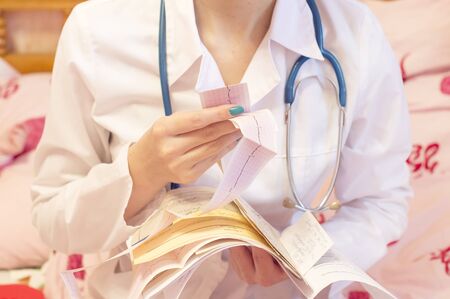 A doctor with a stethoscope and white coat is studying the blood and the patient's medical historyの写真素材