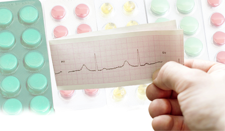 ECG in the hands of doctors against the background of different tablets to treat diseasesの写真素材