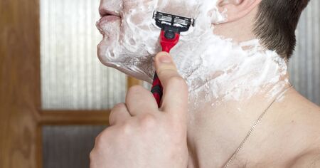 The process of shaving the face with a razor in the bathroomの写真素材