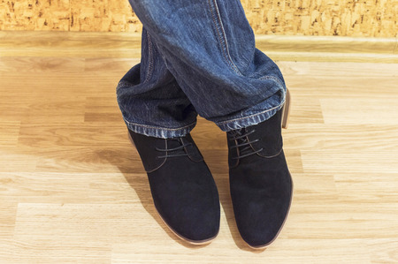 Presentation of new models of men's suede shoes against a wall with wallpaper and wooden parquetの写真素材