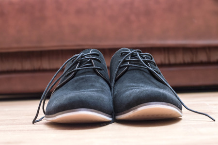 Black suede shoes with laces on a background of the leather couchの写真素材