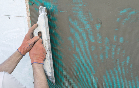 The process of applying putty to the  polyfoam wall using a spatulaの写真素材
