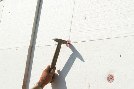 The process of nailing to the wall using a metal hammerの写真素材
