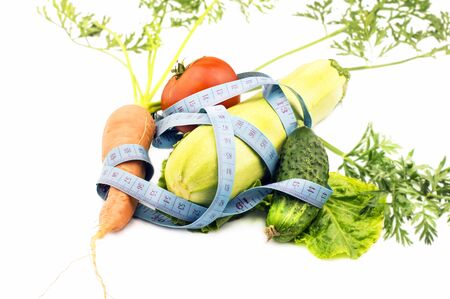 Various vegetables wrapped in measuring tape on a white backgroundの写真素材