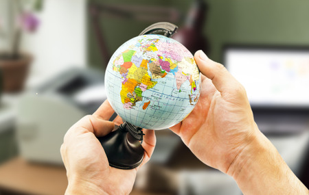 Political globe in the hands on the background blurred office backgroundの写真素材