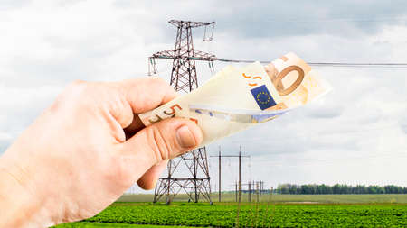 The euro in hand on the background of power lines under the open skyの写真素材