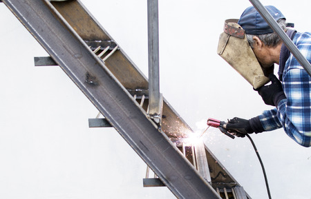 The process of welding metal armature on the background of the white wall