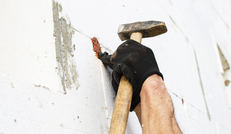 The process of fixing the dowel-umbrella with a hammer in the wall from polyfoamの写真素材